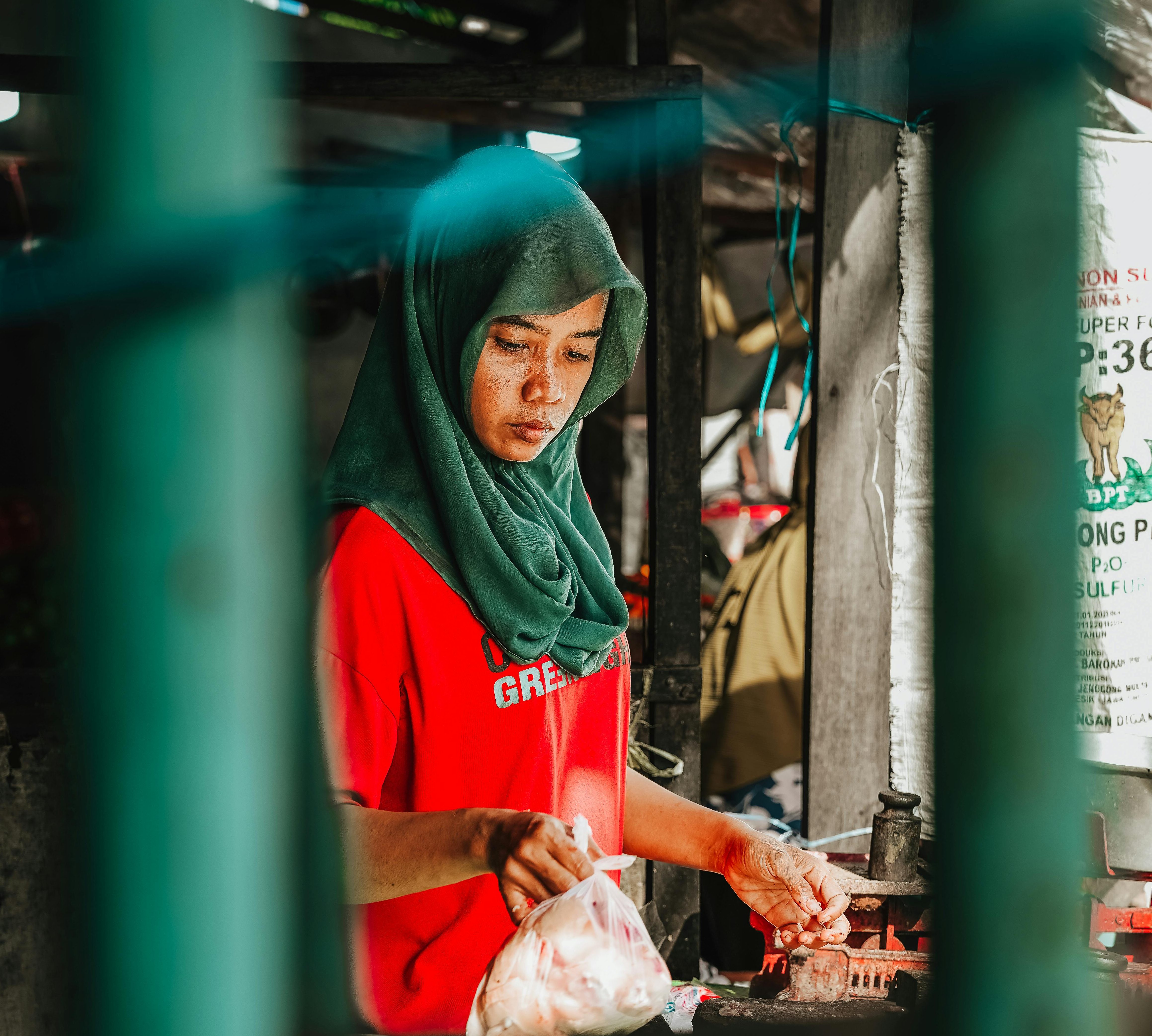 A woman in a traditional market, Surabaya, preparing meat at her stall.